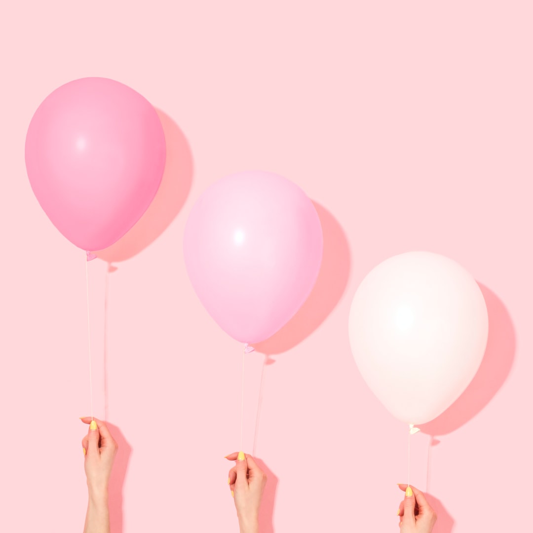 person holding pink and white balloon
