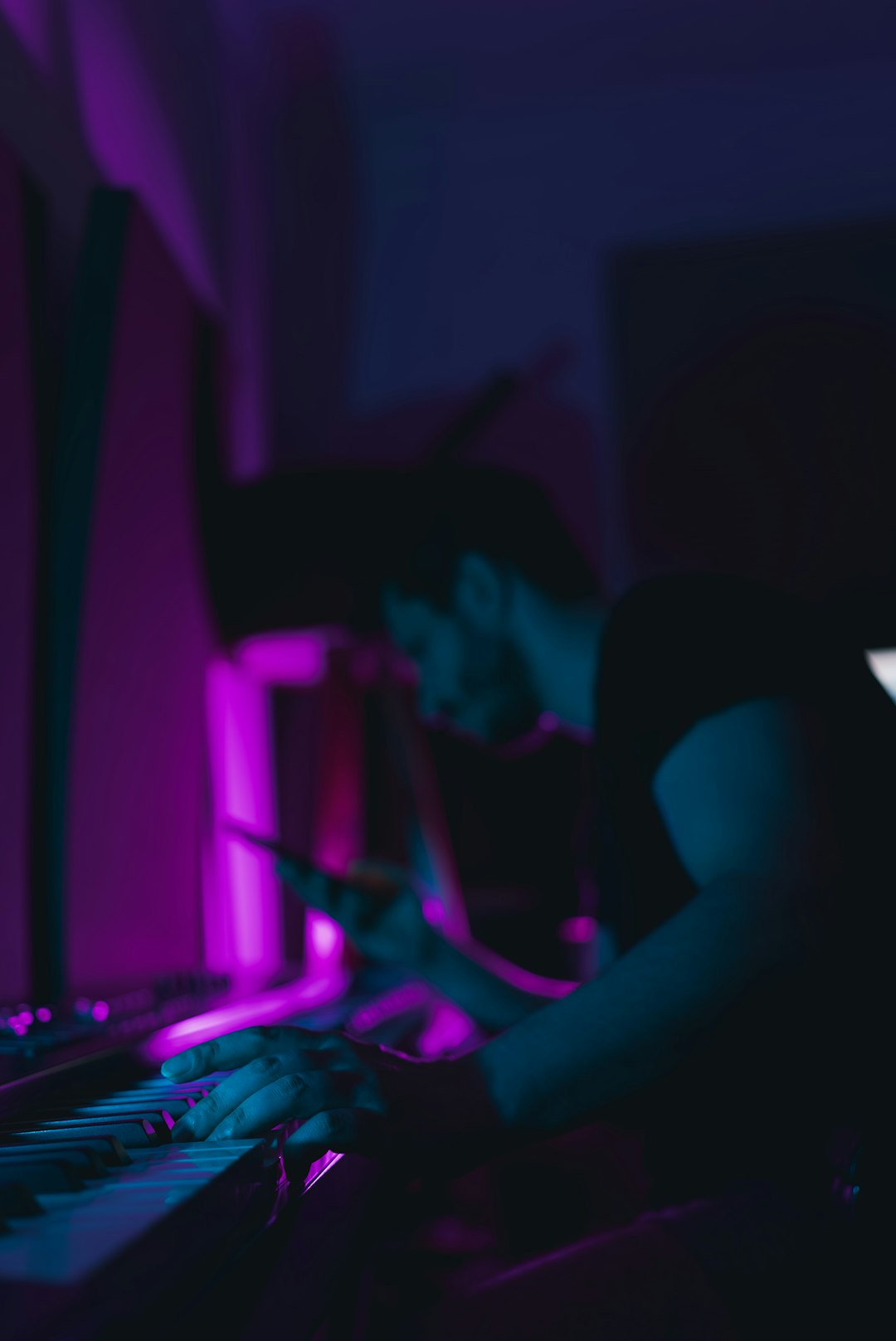 A man sitting in front of a keyboard in a dark room